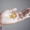 Hand holding yellow capsules, representing supplements and health care.